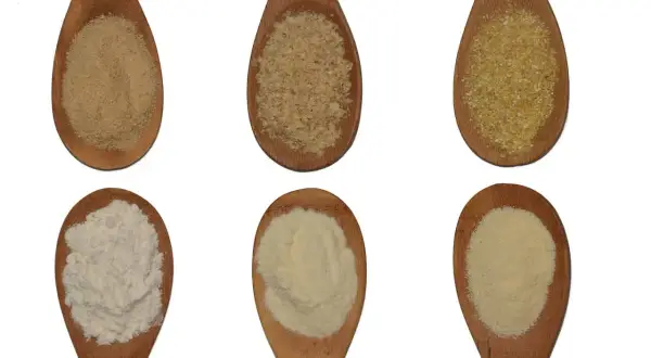 Sei cucchiai di legno mostrano diverse granulosità: dalla semola più fine al semolato più grossolano, per capire la differenza.