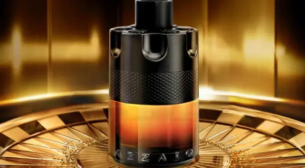 Elegancki flakon perfum Azzaro Wanted w odcieniach czerni i złota, stojący na ozdobnej tacy.