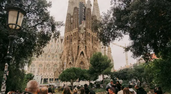 Tłum ludzi podziwia Sagrada Familia. Zastanawiasz się, ile się leci do Barcelony, by zobaczyć to cudo architektury?