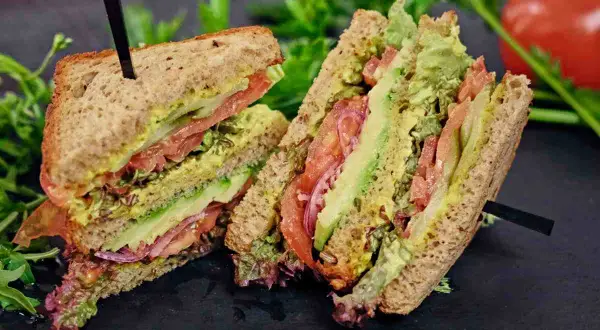 Tramezzini gusti freschi e colorati con avocado, pomodoro, cipolla rossa e insalata su pane integrale.