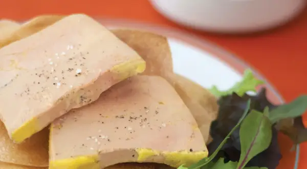 Tranches de foie gras poêlé, assaisonnées de sel et poivre, sur une galette. Le temps de cuisson foie gras bain-marie est crucial pour cette texture.