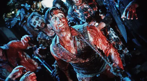 Krwawy mężczyzna otoczony przez zombie. Scena pełna grozy, idealna dla fanów **horrory 18+**.