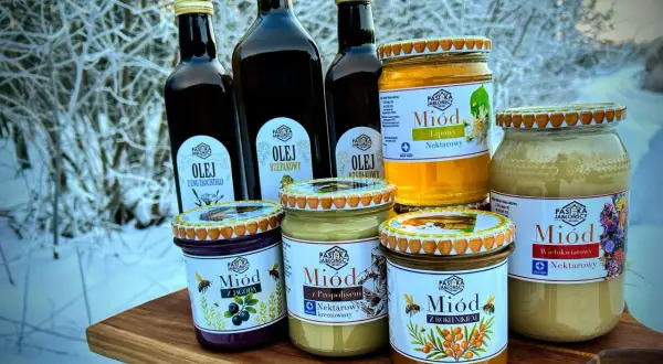 Słoiki z miodem i butelki z olejem na tle zimowego krajobrazu. Miód pitny trójniak ile procent? Sprawdź etykiety!