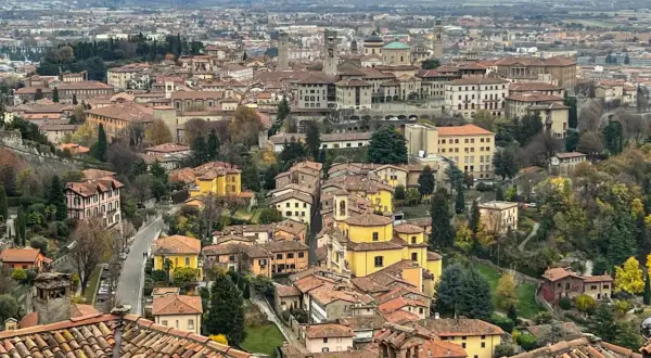 Widok na wzgórza i dachy Bergamo, miasta bliskiego Mediolanowi. W oddali widać góry.