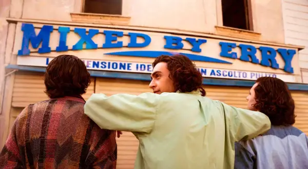 Tre amici guardano un negozio con insegna "MIXED BY ERRY".