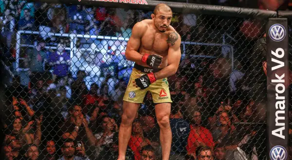 Jose Aldo, en ikonisk MMA-fighter, står i buren, redo att utöka sitt imponerande jose aldo record. Publiken jublar bakom nätet.