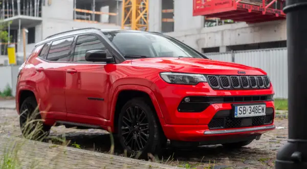 Czerwony Jeep Compass na tle budowy. Wiele osób szuka jeep compass opinie przed zakupem.