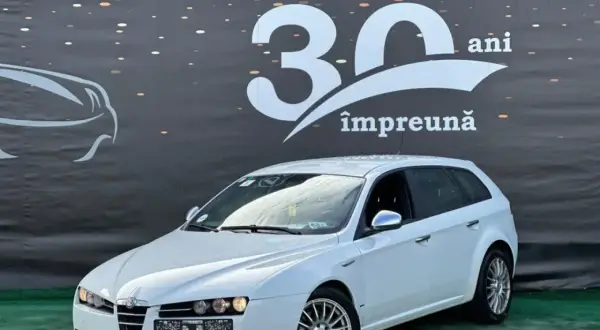 Białe Alfa Romeo 159 1.9 JTD kombi na tle baneru z napisem "30 ani împreună".