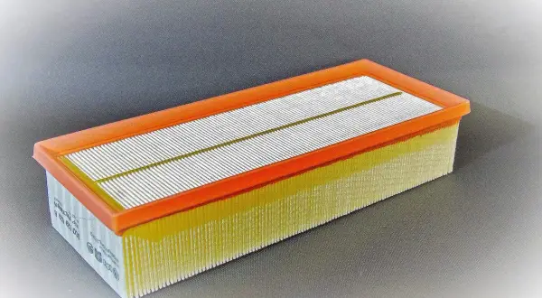 Filtro de aire rectangular con marco naranja y pliegues amarillos. Pregúntate cada cuanto se cambia el filtro de aire para mantener tu motor en óptimas condiciones.