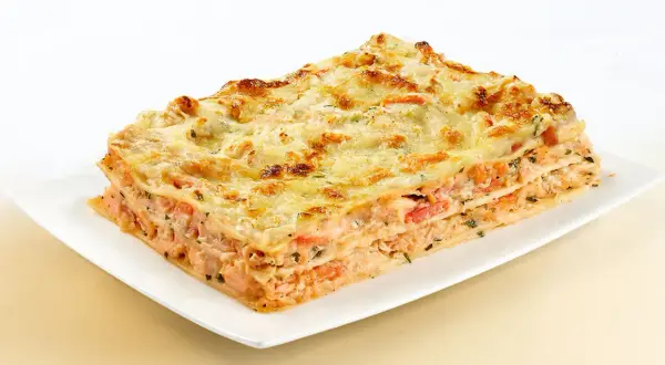 Une part généreuse de lasagne au saumon, avec ses couches de pâtes, de poisson rose et de fromage gratiné, prête à être dégustée.