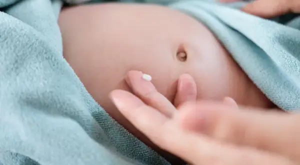 Delikatna skóra niemowlaka, pępek i kropla kremu na palcu. Tak wygląda pielęgnacja, która może pomóc w przypadku przepukliny pępkowej.