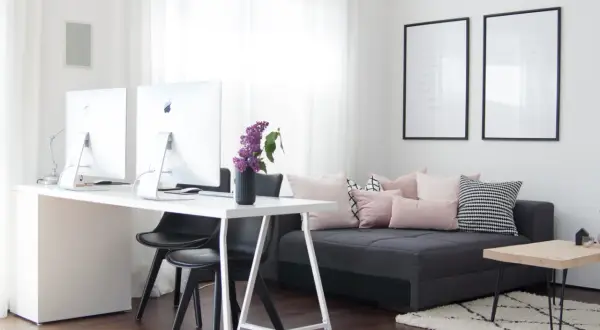 Ein helles Arbeitszimmer mit Schreibtisch, zwei Computern und einem gemütlichen Sofa, das zum Einrichten einlädt.