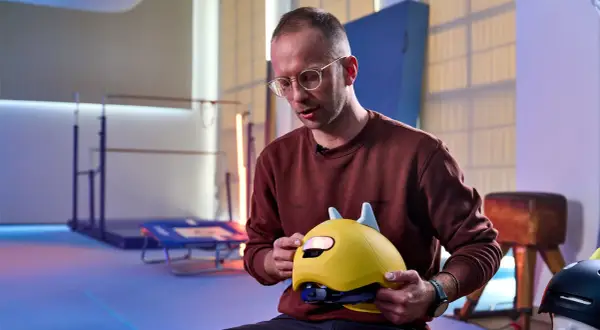 Mann erklärt, wie muss ein Fahrradhelm sitzen: Kinderhelm mit Ohren, gut angepasst und sicher.