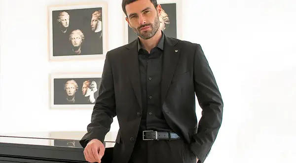 Uomo con abito nero, camicia e cravatta abbinati. Eleganza senza tempo.