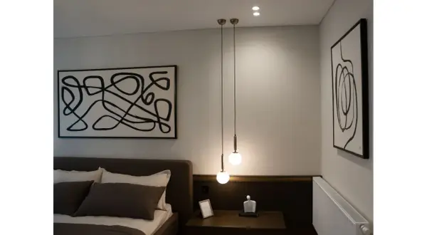 Dwa wiszące punkty świetlne tworzą nowoczesny żyrandol szary nad stolikiem nocnym.