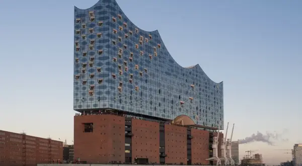 Elbphilharmonie Hamburg mit Glasfassade und Backsteinsockel am Wasser.