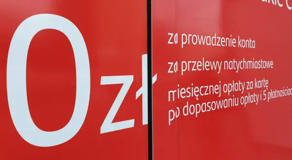 Na czerwonym tle biały napis "0zł" i lista opłat za konto, przelewy i kartę w Santander.
