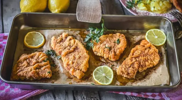 Vier saftige putenschnitzel im Ofen gebacken, garniert mit frischer Petersilie und Zitronenspalten.