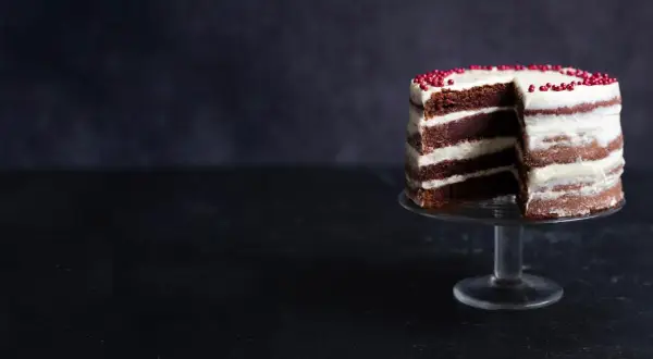 En läcker red velvet cake med lager av choklad och krämig frosting, dekorerad med röda pärlor.