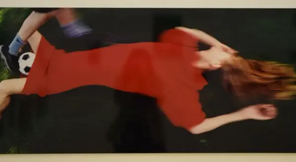 Boris Mikhailov cattura un momento di movimento sfocato: una donna in abito rosso e un piede con pallone da calcio.