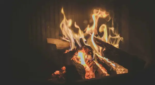 Glühendes Kaminfeuer mit Holzscheiten. Die brennholz trocknen dauer tabelle ist hier nicht sichtbar, aber das Feuer wärmt.