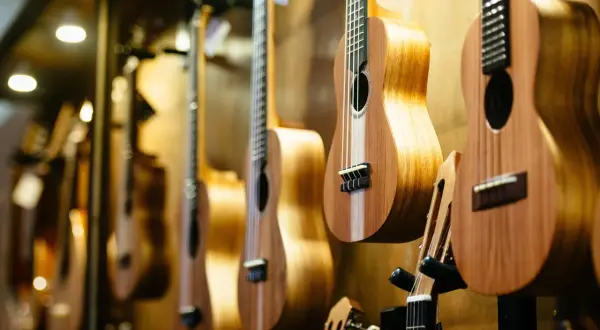 Rząd drewnianych ukulele wiszących na ścianie, z bliska.