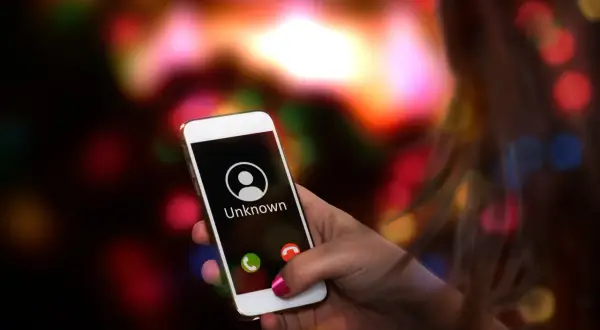 Dłoń trzyma smartfon Samsung z ekranem pokazującym przychodzące połączenie od nieznanego numeru. Chcesz wiedzieć, jak wyłączyć numer prywatny Samsung?