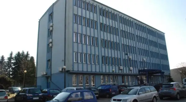 Budynek miejskiego ośrodka pomocy społecznej w Dąbrowie Górniczej, z zaparkowanymi samochodami przed wejściem.