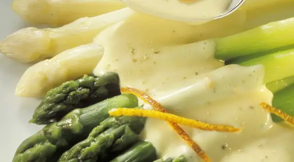 Frischer Spargel, weiß und grün, wird mit einer cremigen Sauce und Orangenzesten serviert. Perfekt zum Spargel kochen.
