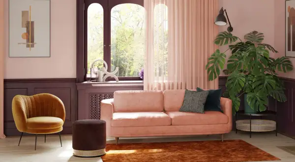 Ein pfirsichfarbenes Sofa mit modernen Kissen, umgeben von warmen Tönen, zeigt, welche Sofa Farbe ist modern. Ein gelber Sessel und ein brauner Hocker ergänzen den Look.