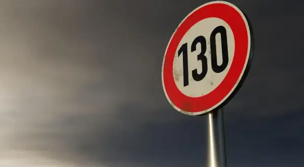 Znak ograniczenia prędkości 130 km/h na tle burzowego nieba, typowy dla autostrad w Niemczech.