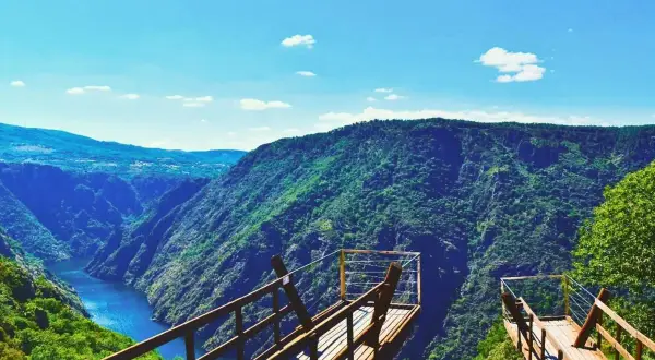 Mirador de madera con vistas a un cañón verde y un río azul. Imprescindible que ver en Ribeira para disfrutar de la naturaleza.