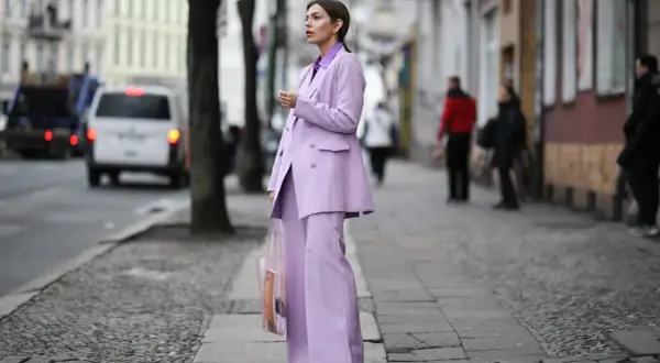 Elegancki garnitur w kolorze liliowym z czym łączyć? Modelka prezentuje stylizację z żółtymi czółenkami i transparentną torbą.