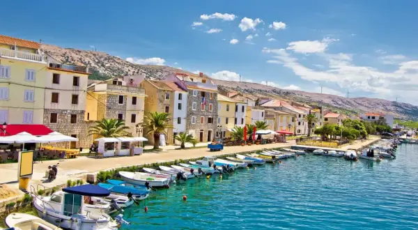 En kuststad i Kroatien med färgglada hus, en hamn full av båtar och en bergig bakgrund. Här finns fakta om Kroatien.