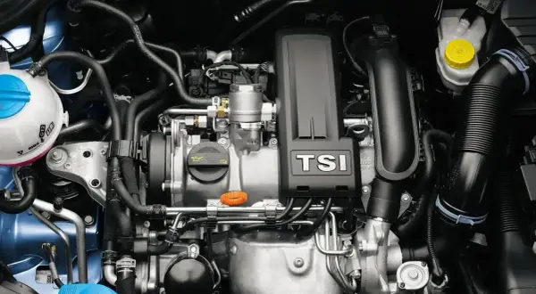 Silnik 1.2 TSI EA211 z turbosprężarką. Widoczne elementy układu chłodzenia, dolot powietrza i osłona silnika z napisem TSI.