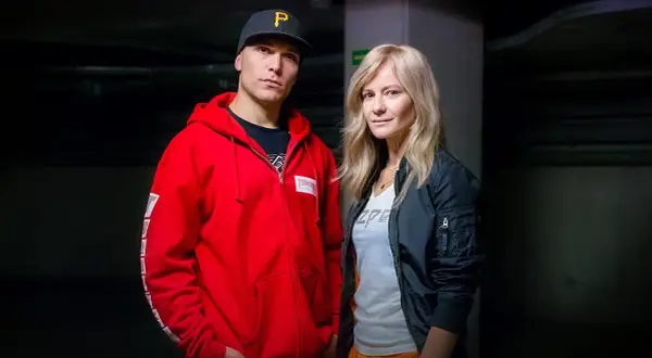 Tomasz Chada z żoną, w ciemnym korytarzu. On w czerwonej bluzie i czapce, ona w czarnej kurtce.