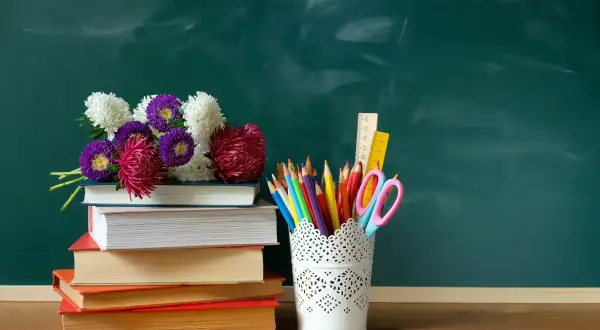 Kwiaty na stosie książek i przybory szkolne. Idealny zestaw na 14 maja święto.