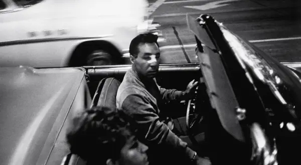 Garry Winogrand uchwycił nocną jazdę kabrioletem. Mężczyzna za kierownicą, kobieta obok. Rozmyte światła miasta.