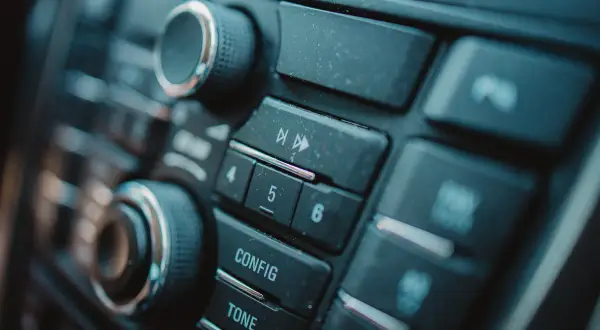 Dettaglio del pannello di un'autoradio, con manopole e pulsanti per il montaggio e la configurazione.