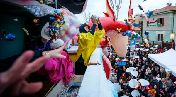Carnevale a Fano: dolciumi volano da un carro allegorico tra la folla festante.