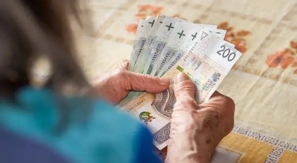 Dłonie liczą polskie banknoty, symbolizujące kapitał początkowy na nowy projekt.