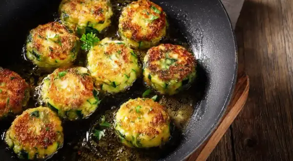 Zucchini puffer in einer Pfanne braten. Goldbraun und knusprig, mit frischer Petersilie garniert.