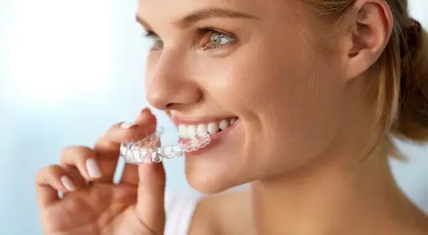 Donna sorridente mostra il suo invisalign indossato, un sorriso smagliante in arrivo.