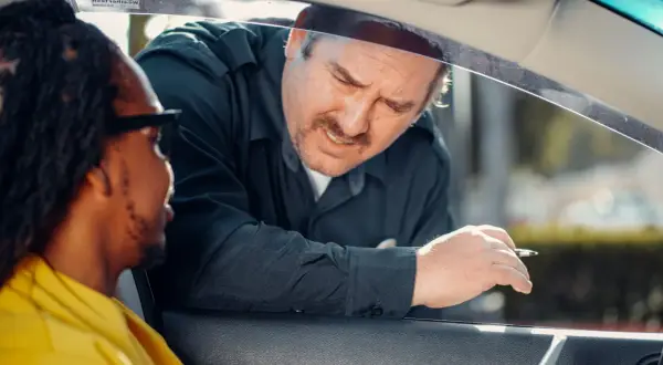 Un policier demande des papiers à un conducteur. Il espère que son nouveau permis de conduire, validité 5 ans, sera en règle.