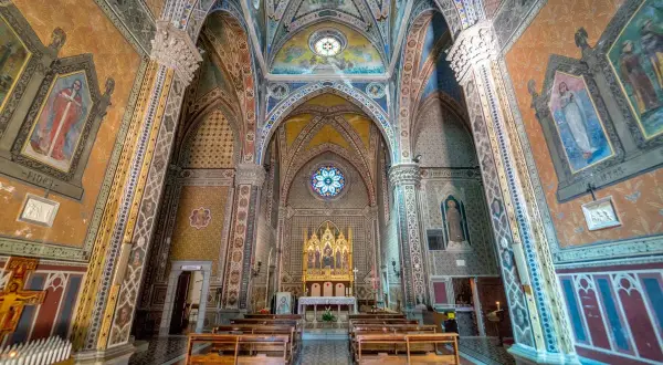Interno di un santuario in Emilia Romagna, con affreschi colorati, volte decorate e un altare dorato.