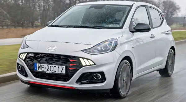 Biały Hyundai i10 N Line w ruchu, z widocznym grillem i światłami LED. Sprawdź aktualną hyundai i10 cena.