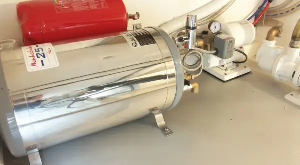 Boiler nautico in acciaio inox e serbatoio rosso. Preparazione per svuotare boiler inverno, con pompe e tubazioni.