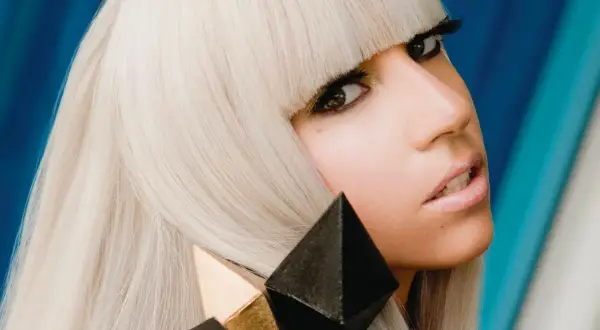 Lady Gaga con i suoi iconici capelli biondi e un look audace, ricorda la sua prima canzone.
