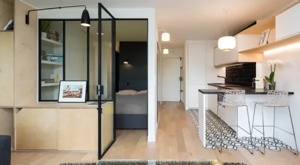 Interno di moderni mini appartamenti con zona giorno, cucina a vista e camera da letto separata da vetrata.