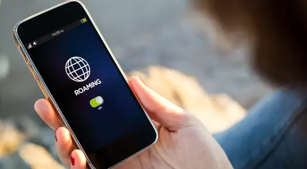 Telefon pokazuje ikonę globu i napis "ROAMING" z włączonym przełącznikiem. To oznacza, że funkcja roamingu jest aktywna.